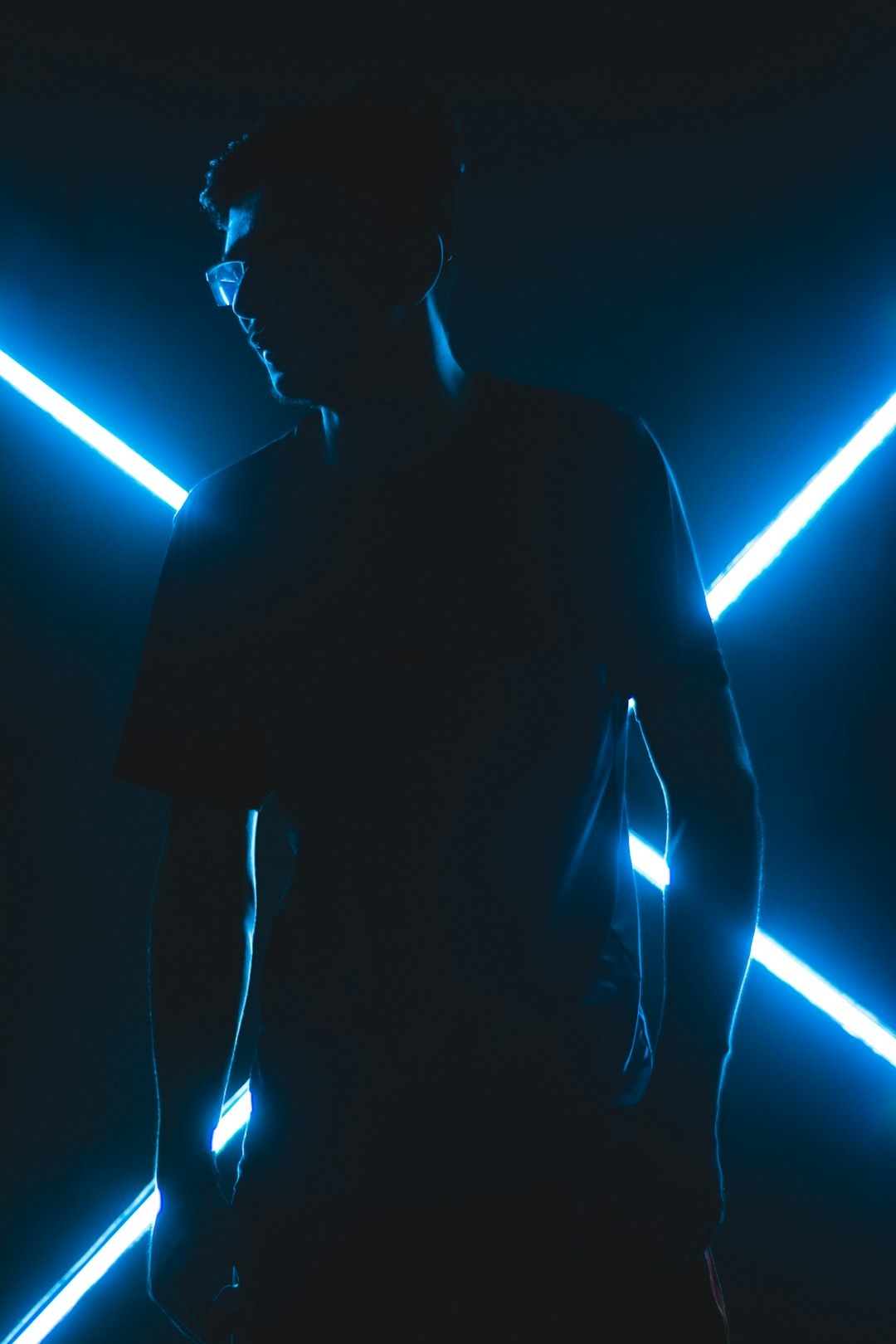 Person wearing glasses in blue neon light.
