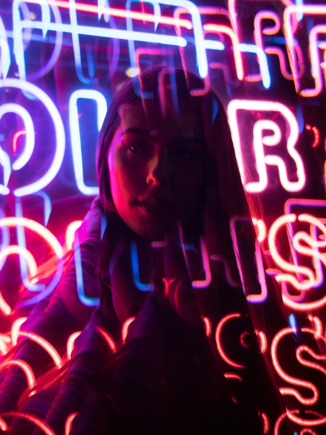 Woman standing in front of illuminated neon street signs.
